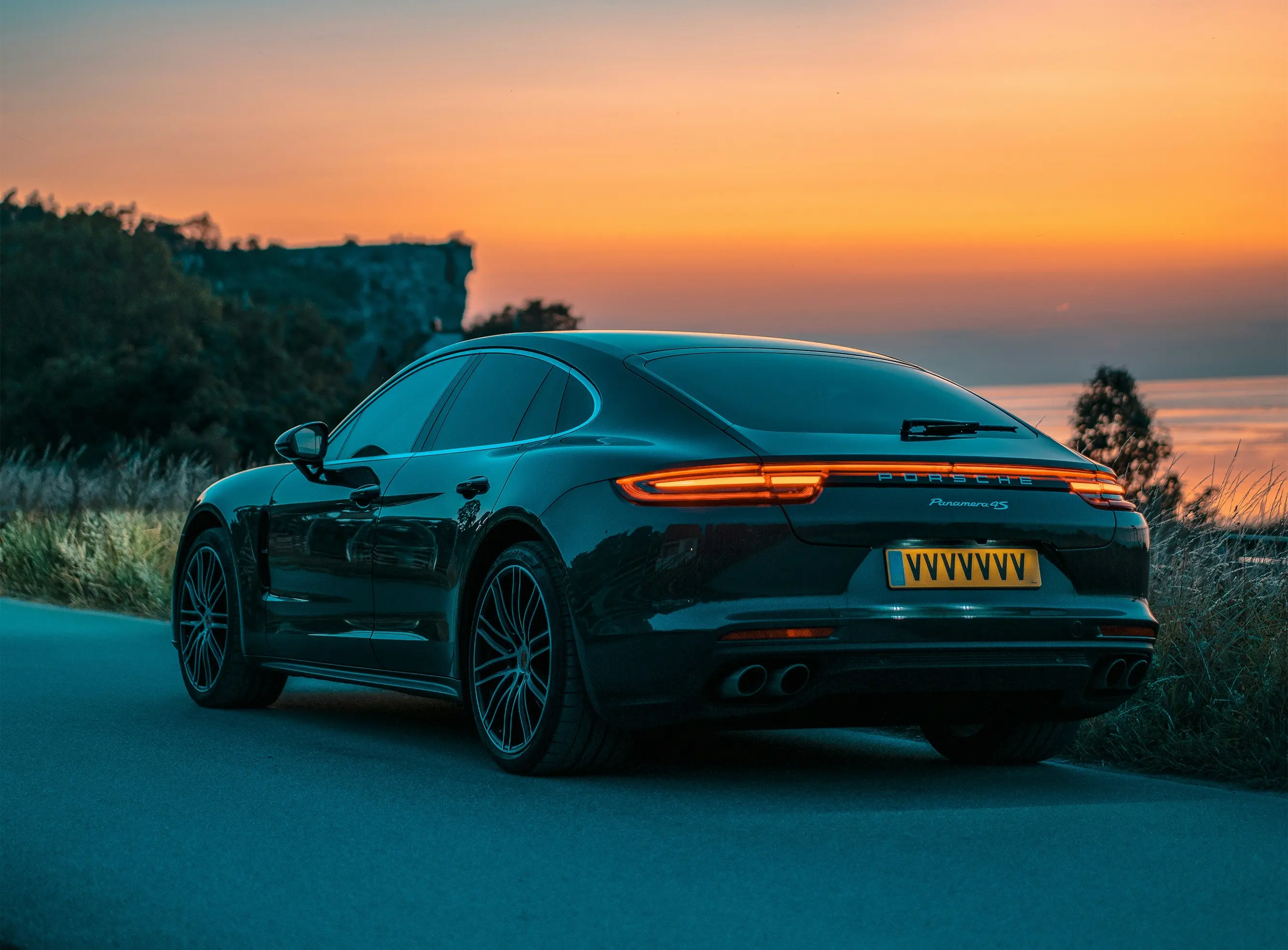 Black sports car parked on a road during sunset.