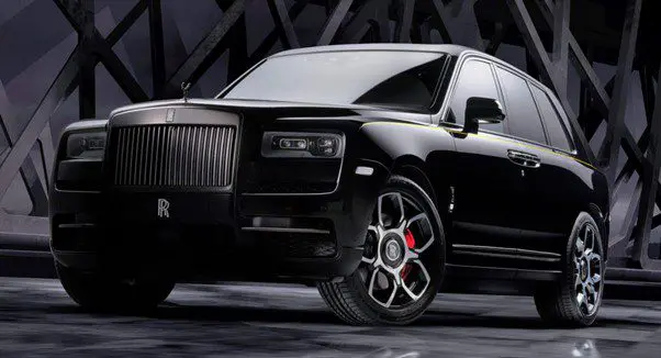 Close-up of a luxury black Rolls-Royce car with distinctive grille and wheel design.